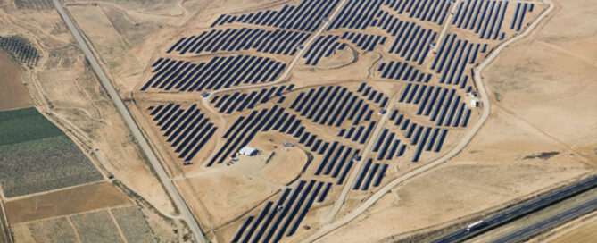 Vista aérea de una gran planta solar fotovoltaica en un desierto con filas de paneles solares