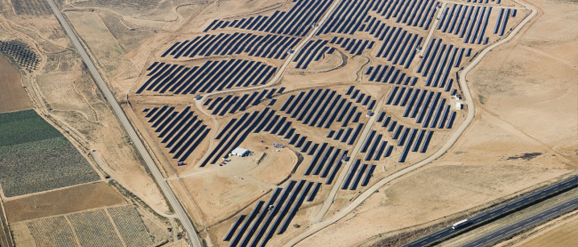 Vista aérea de una gran planta solar fotovoltaica en un desierto con filas de paneles solares