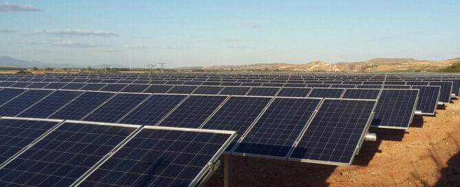 Planta solar fotovoltaica en terreno árido con filas de paneles solares generando energía renovable