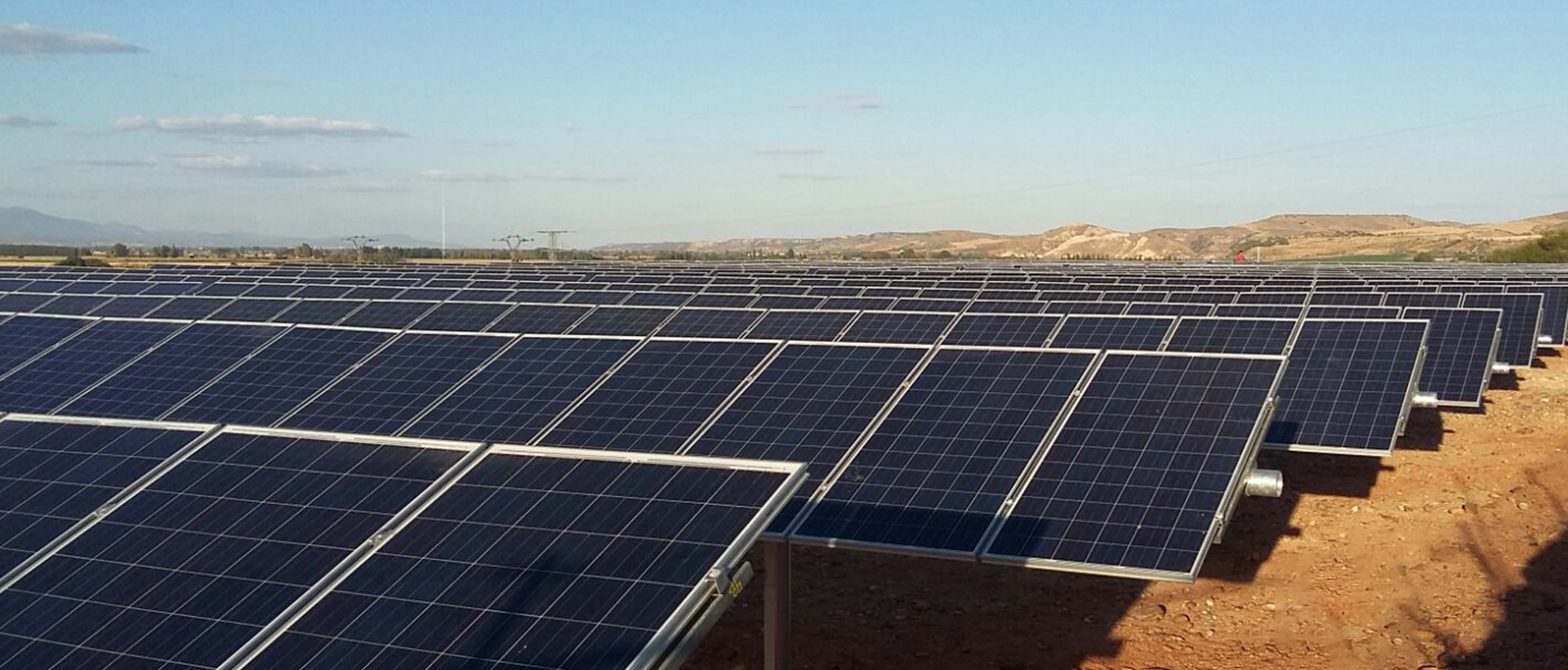 Planta solar fotovoltaica en terreno árido con filas de paneles solares generando energía renovable