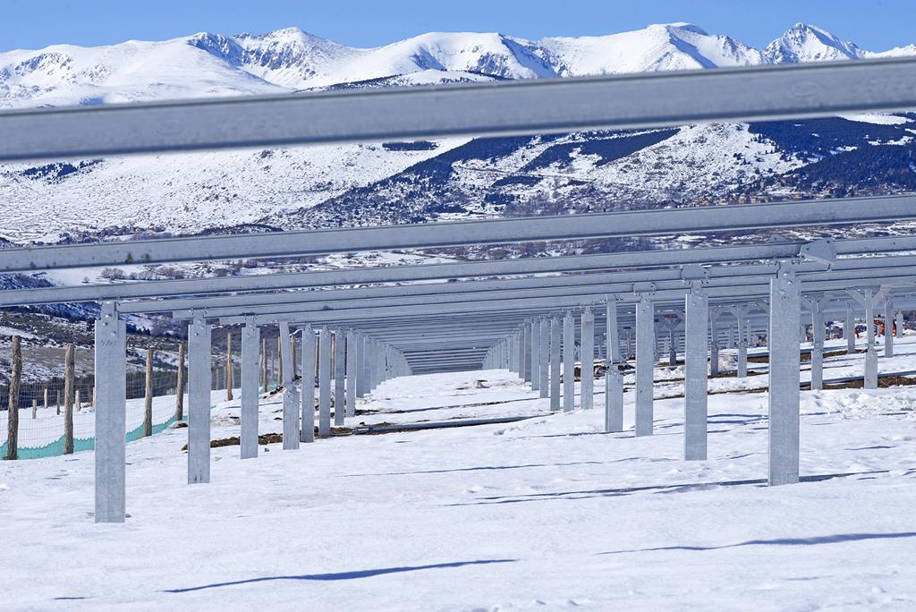 Estructuras metálicas para paneles solares instaladas en un campo nevado con montañas al fondo