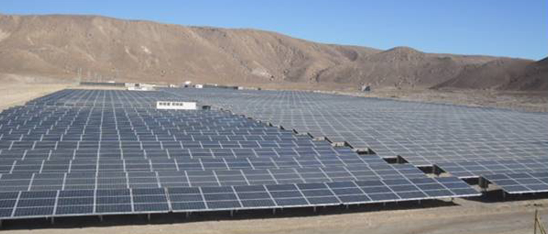 Paneles solares fotovoltaicos instalados en un campo con montañas de fondo para generación de energía renovable