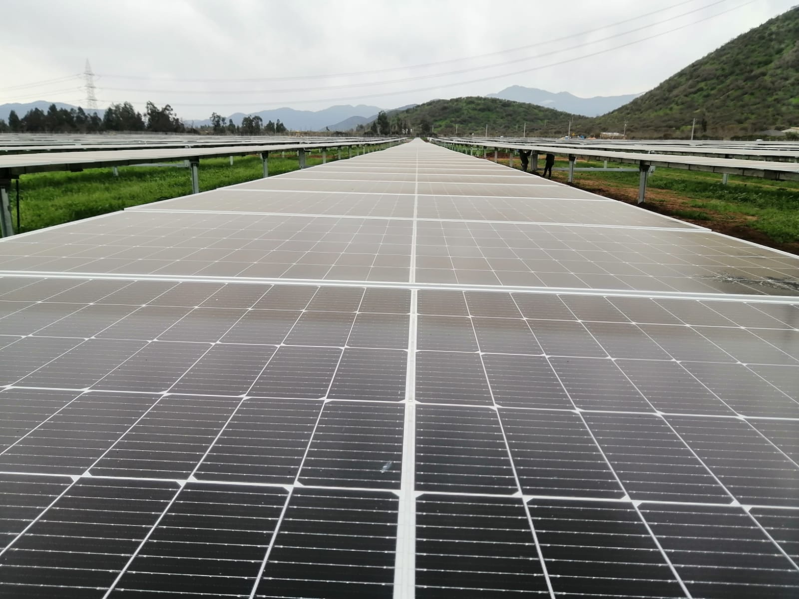 Paneles solares fotovoltaicos instalados en un campo con montañas de fondo para generación de energía renovable