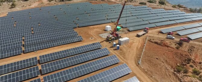 Construcción de planta solar fotovoltaica en zona desértica con paneles solares y grúa en operación