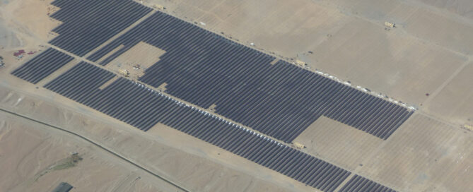 Vista aérea de una planta solar fotovoltaica en el desierto con miles de paneles solares alineados