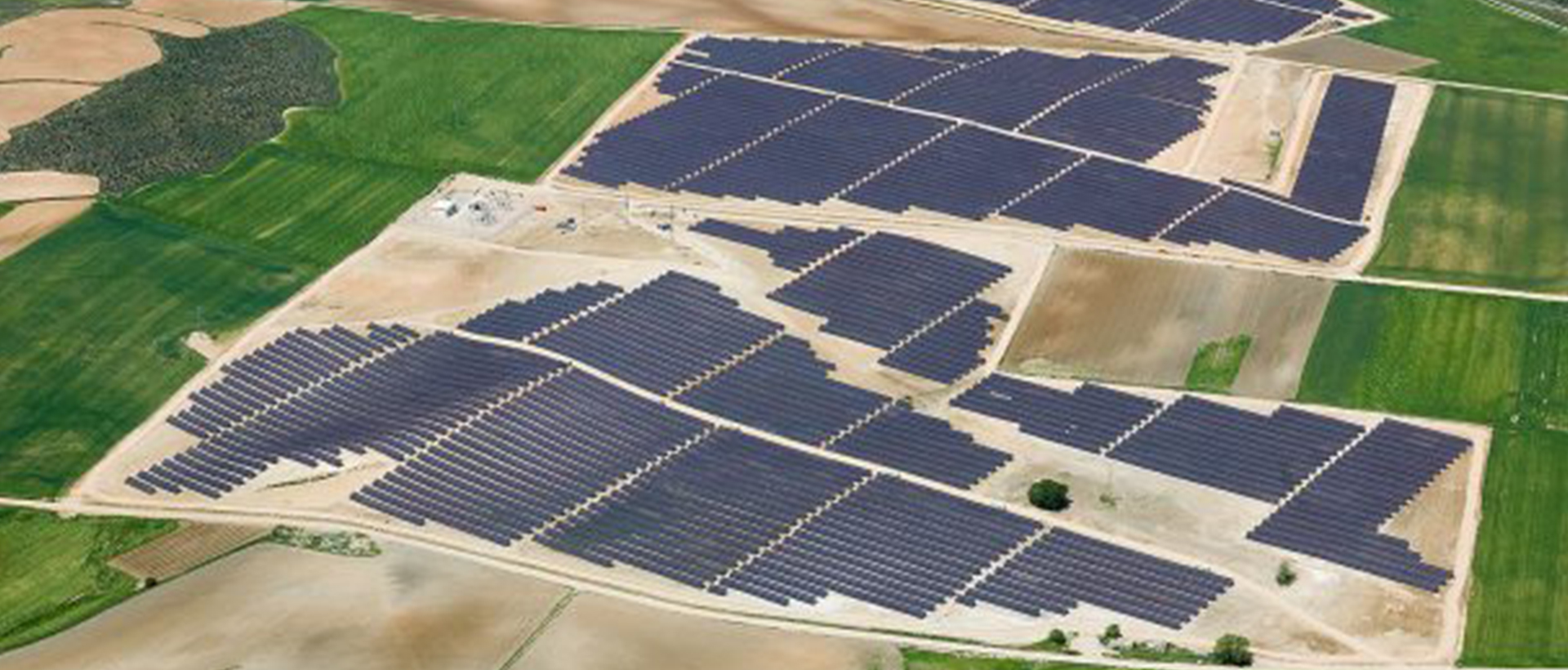 Vista aérea de una planta solar fotovoltaica con seguidores a un eje en terreno agrícola